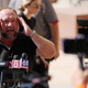 Jones standing by a cluster of microphones with his hands to his head.